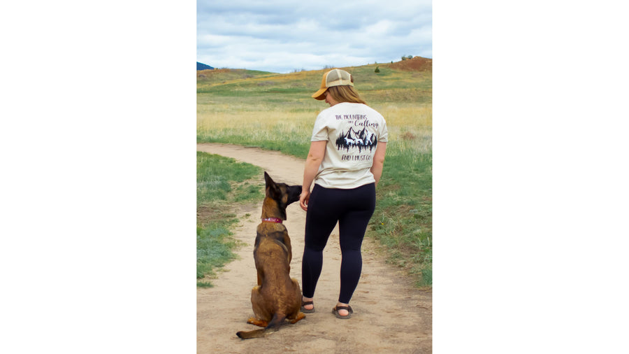 Shirt — cream Mountains Are Calling tee worn on a prairie trail with a Malinois